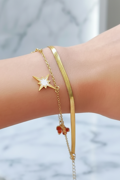 Coco pearls stainless Steel anti tarnish Gold wish upon bracelet with star-shaped and clover charms on a wrist against a blurred background