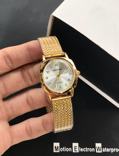Gold wristwatch held in a hand with a blurred background