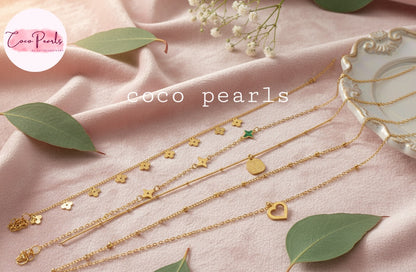 Coco Pearls Stainless Steel Anti Tarnish Gold delight bracelets and anklets with various pendants on a pink fabric background