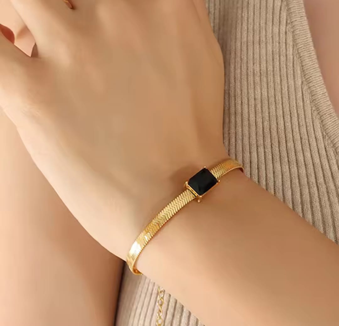 Coco Pearls Stainless Steel Anti Tarnish Gold black accent bracelet with a black stone and snake chain on a wrist against a neutral background