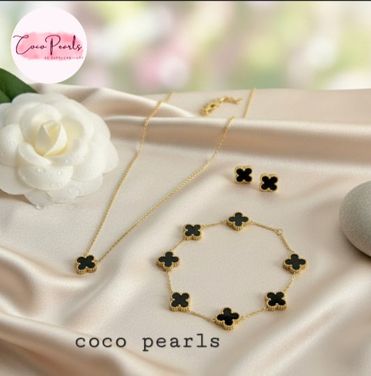 Coco Pearls Stainless Steel Anti Tarnish black clover dotted Jewelry set with necklace, bracelet, and earrings on a soft fabric background