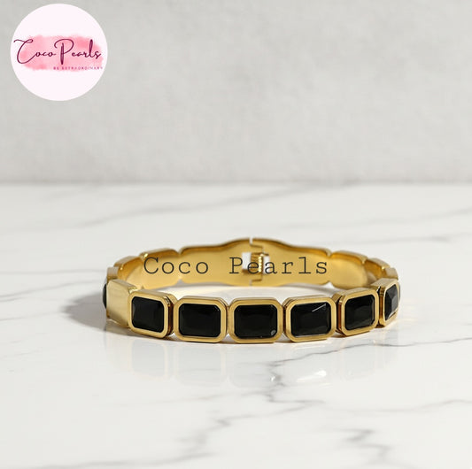 Coco Pearls Stainless Steel Anti Tarnish Gold black gem handcuff bangle bracelet with black square stones on a white marble surface