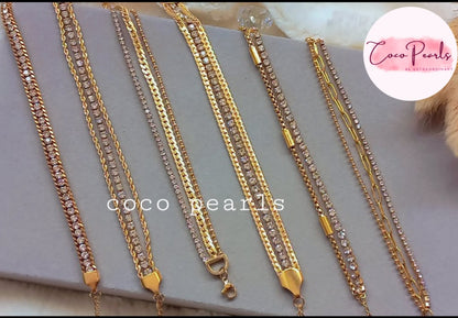 Coco Pearls Stainless Steel Anti tarnish Gold bracelets stack. Gold bracelets with rhinestones displayed on a gray surface