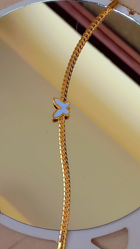 Coco Pearls Stainless Steel Anti Tarnish Gold butterfly bliss bracelet with a white butterfly charm mesh chain on a reflective gold surface