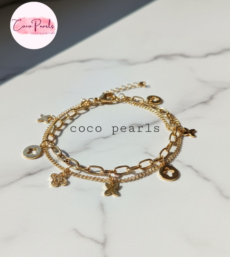 Coco Pearls Stainless steel anti tarnish Gold charm layered bracelet with charms on a marble surface