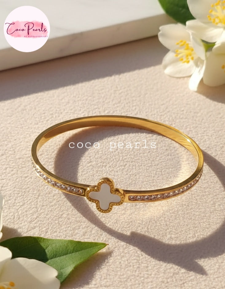 Coco Pearls Stainless Steel Anti tarnish gold clover luxe handcuff with zircon on sides and clover in center displayed on simple background