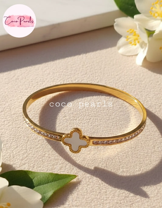 Coco Pearls Stainless Steel Anti tarnish gold clover luxe handcuff with zircon on sides and clover in center displayed on simple background