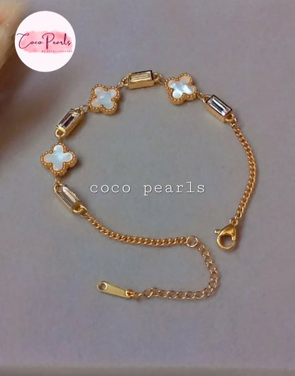 Coco Pearls Stainless Steel Anti Tarnish Gold clover tube bracelet with clover and stones on a simple background.