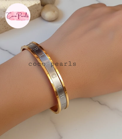 Coco Pearls Stainless Steel Anti Tarnish Gold and silver coco glitz bangle bracelet on a wrist.