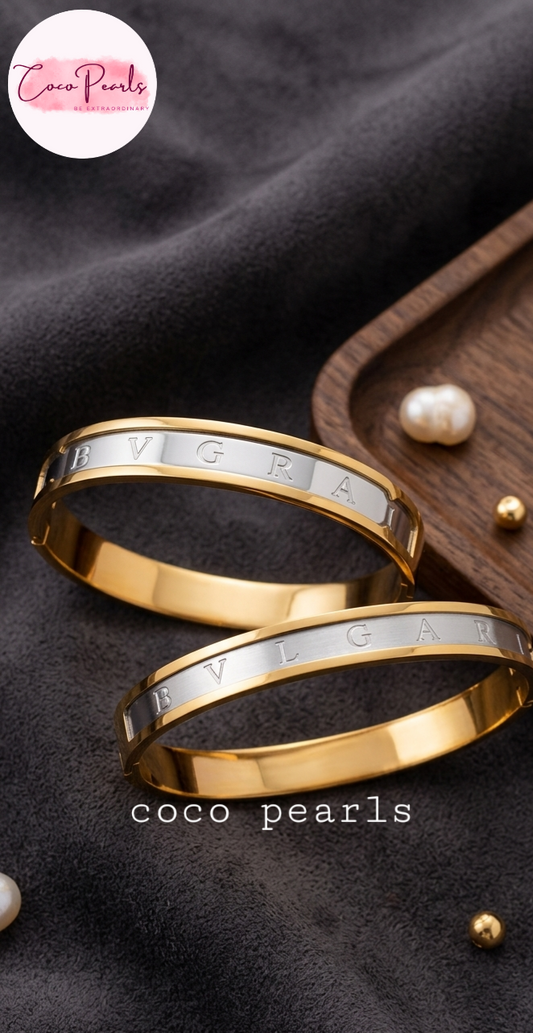 Coco Pearls Stainless Steel Anti Tarnish Two coco glitz gold handcuff bracelets with engraved text on a dark background