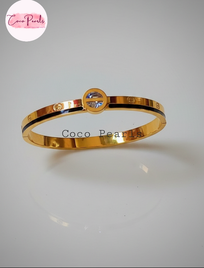 Coco Pearls Stainless Steel Anti Tarnish Gold coco loop handcuff bangle bracelet with a central gemstone and a black line on a white background