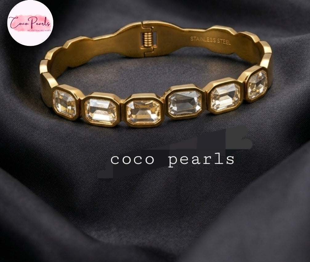 Coco Pearls Stainless Steel Anti Tarnish Gold crystal glam handcuff bangle bracelet with rectangular clear stones on a marble surface