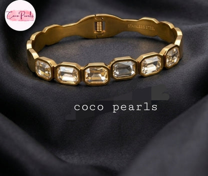 Coco Pearls Stainless Steel Anti Tarnish Gold crystal glam handcuff bangle bracelet with rectangular clear stones on a marble surface