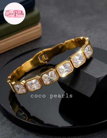Coco Pearls Stainless Steel Anti Tarnish Gold crystal glam handcuff bangle bracelet with rectangular clear stones on a marble surface