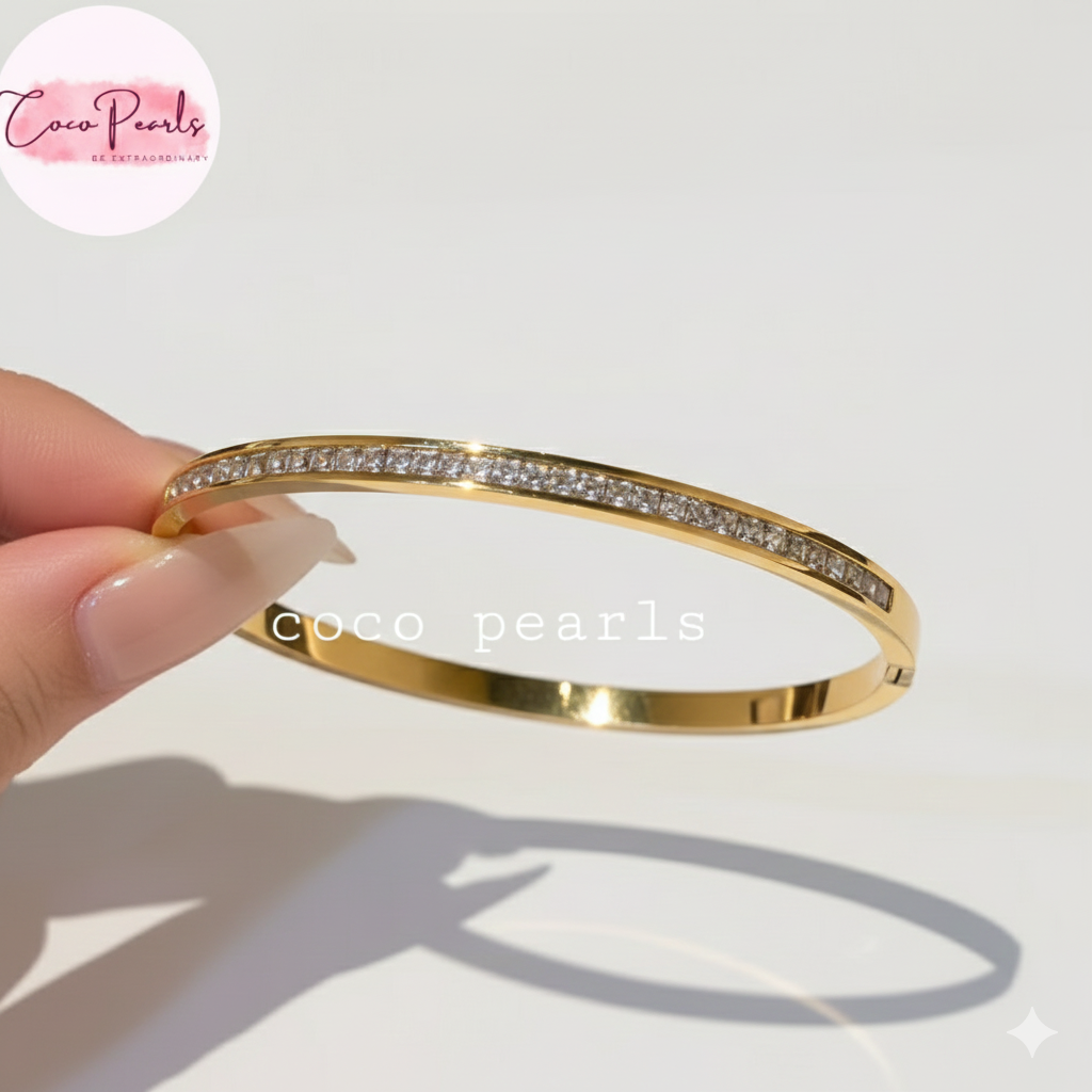 Coco Pearls Stainless Steel Anti tarnish gold crystal shine handcuff bracelet with zircon studded bracelet with clear stones held by a hand