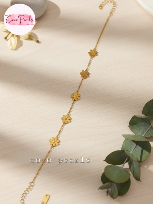 Coco Pearls Stainless steel anti tarnish Gold floral necklace on a beige surface with green leaves 