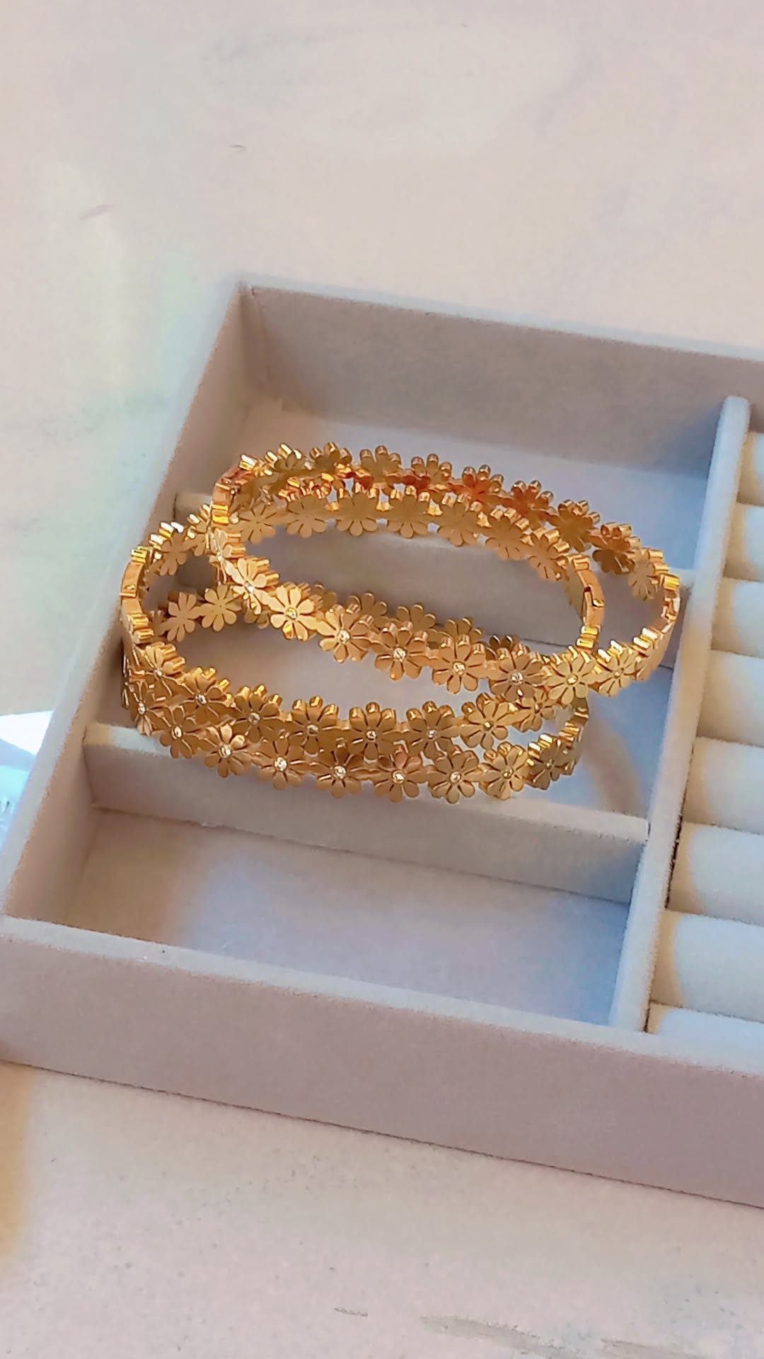 Coco Pearls Stainless Steel Anti Tarnish Gold daisy bloom floral bangle bracelet in a jewelry box on a light background