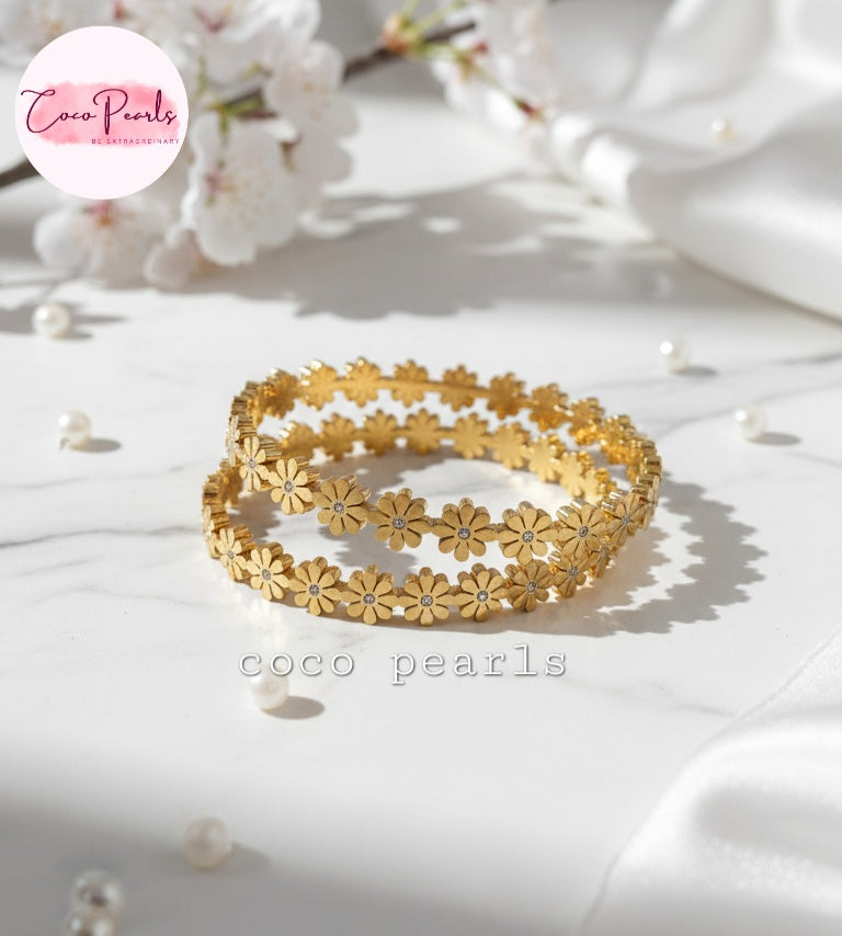 Coco Pearls Stainless Steel Anti Tarnish Gold daisy bloom floral bangle bracelet  on a white surface with 