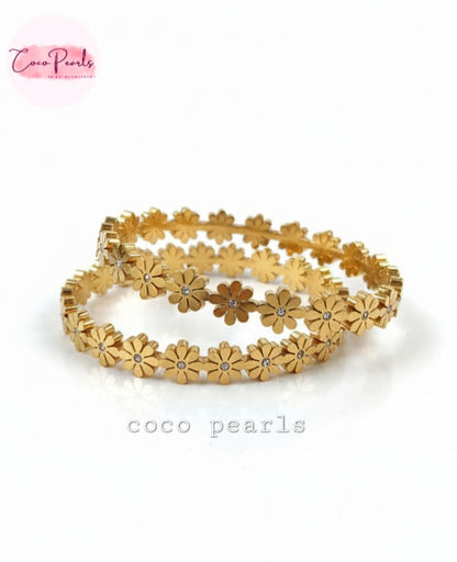 Coco Pearls Stainless Steel Anti Tarnish Gold daisy bloom floral bangle bracelet. Set of gold floral bangleson a white background