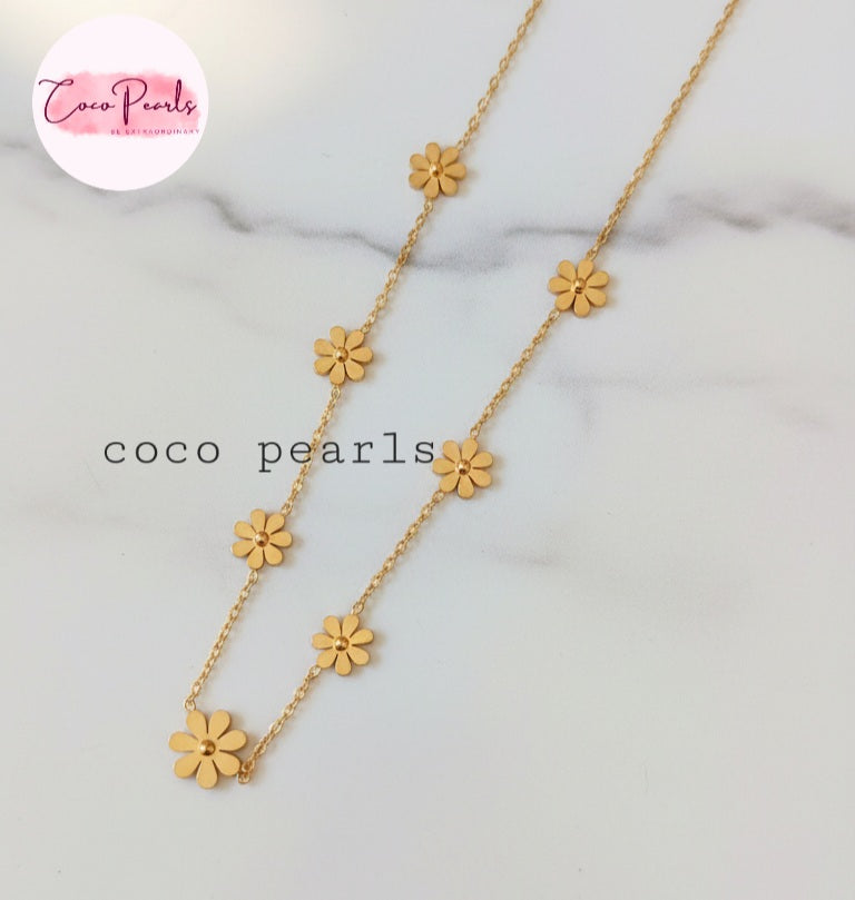 Coco Pearls Stainless Steel Anti Tarnish Gold daisy bloom necklace with flower pendants on a marble background
