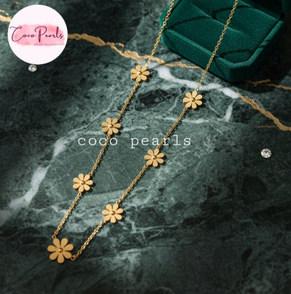 Coco Pearls Stainless Steel Anti Tarnish Gold daisy bloom necklace with flower pendants on a dark marble surface
