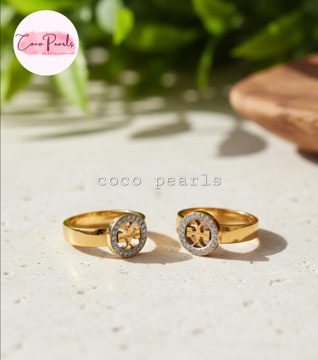 Coco Pearls Stainless Steel Anti Tarnish Two dazzle gold rings with decorative elements. diamond studded circular charm on a gold and on a simple background
