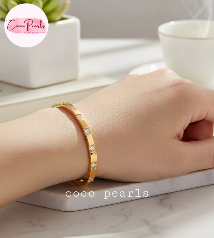 Coco Pearls Stainless Steel Anti tarnish gold diamond radiance handcuff bangle bracelet with tones embedded displayed on a hand