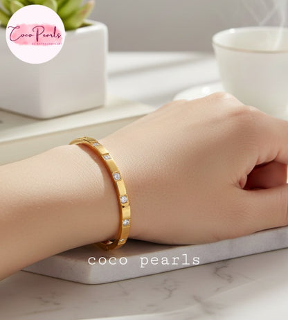 Coco Pearls Stainless Steel Anti tarnish gold diamond radiance handcuff bangle bracelet with tones embedded displayed on a hand