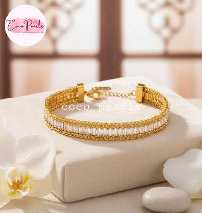 Coco Pearls Stainless Steel Anti Tarnish Gold elegant twist bracelet with white stones on a beige surface 