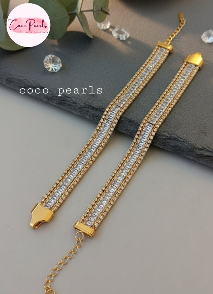 Coco Pearls Stainless Steel Anti Tarnish Gold elegant twist bracelet with clear stones on a gray surface