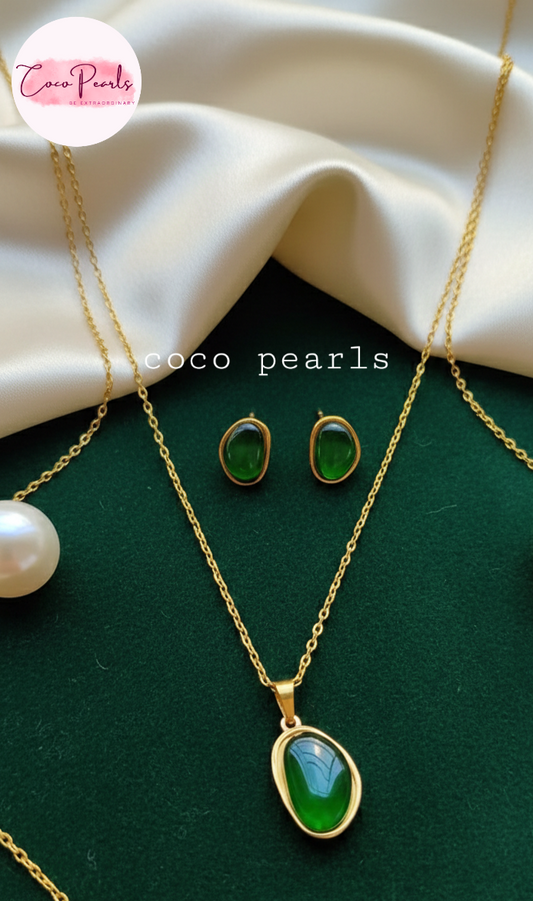 coco pearls stainless steel anti tarnish gold Jewelry set with green gemstones and gold accents on a green surface