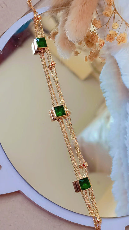 Coco Pearls Stainless Steel Anti Tarnish Gold emerald trio bracelet with three green gemstones on a reflective surface