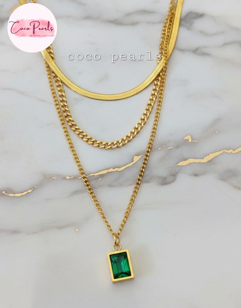 Coco Pearls Stainless Steel Anti Tarnish Gold emerald trio triple chain necklace with a green pendant displayed on a marble background