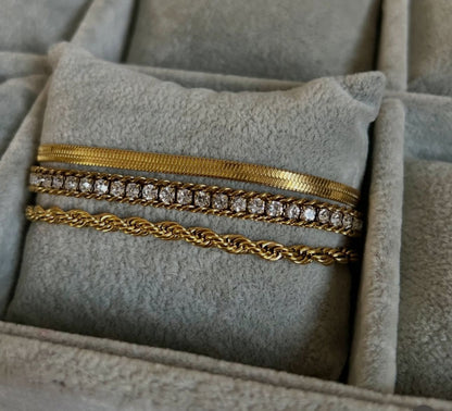 Coco Pearls Stainless Steel Anti Tarnish three Gold eternal shine bracelets stack with diamond accents  bracelet, snake bracelet and rope bracelet on a soft gray pillow