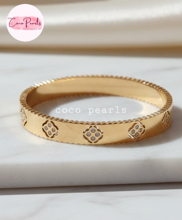 Coco Pearls Stainless Steel Anti tarnish Gold eternal bloom handcuff with diamond-like stones on a white surface