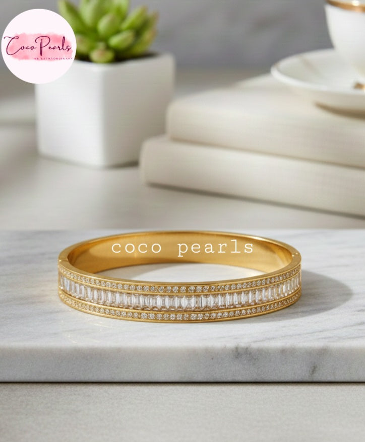 Coco Pearls Stainless Steel Anti tarnish Gold Eternal Spark Handcuff bangle bracelet with zircon and diamonds studded displayed on  marble surface
