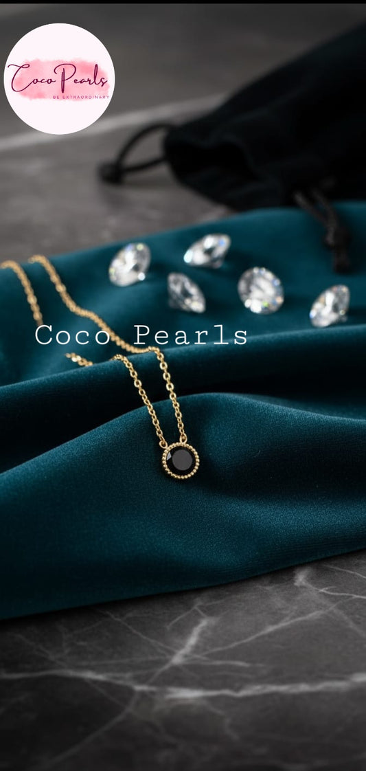 Coco Pearls Stainless Steel Anti Tarnish gem stone glam Gold necklace with a black milestone  pendant on a teal cloth