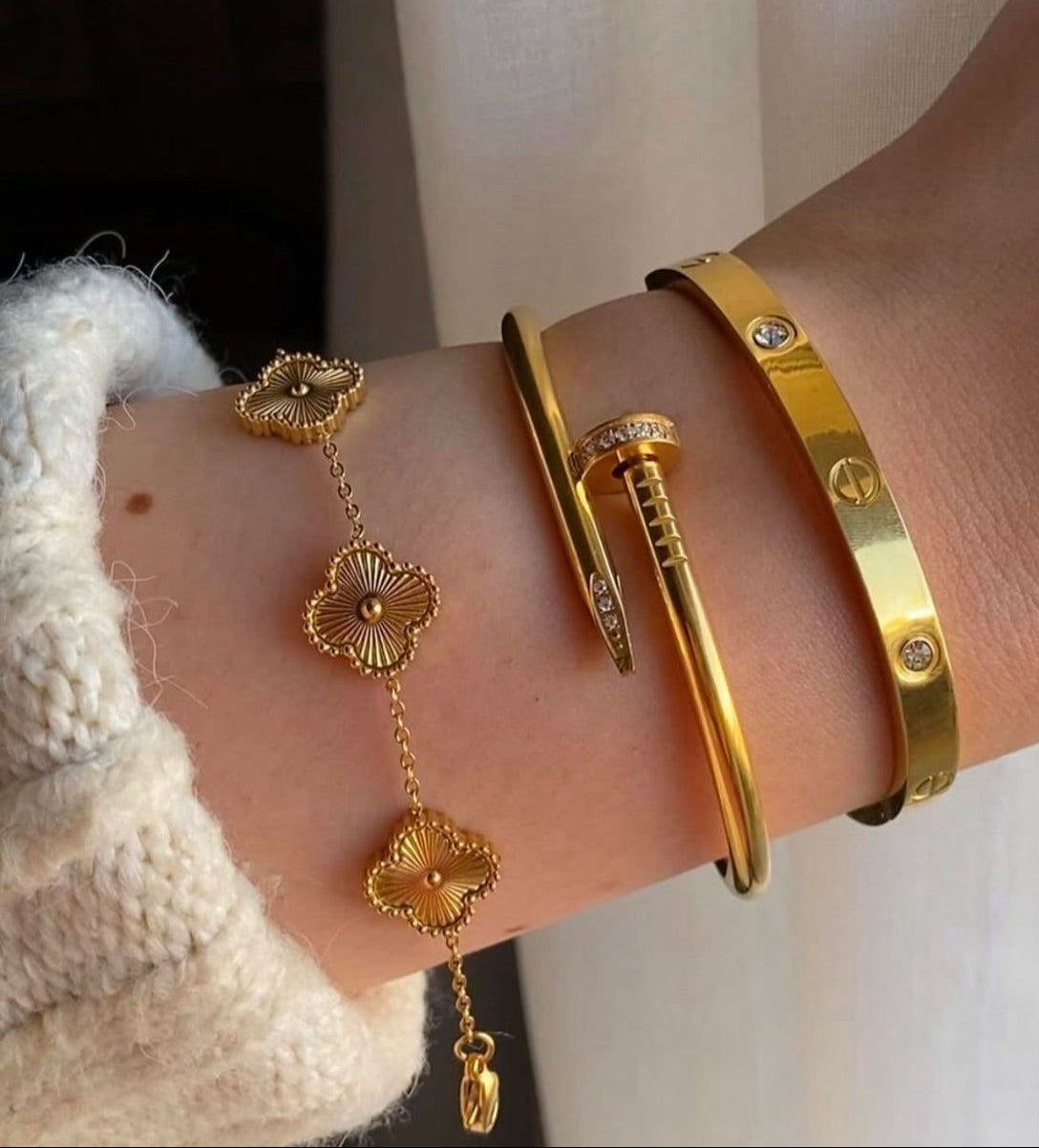 Coco Pearls Stainless Steel Anti Tarnish Golden aura combo bracelets  with golden clover bracelet, nail handcuff and cartier handcuff on a wrist with a neutral background