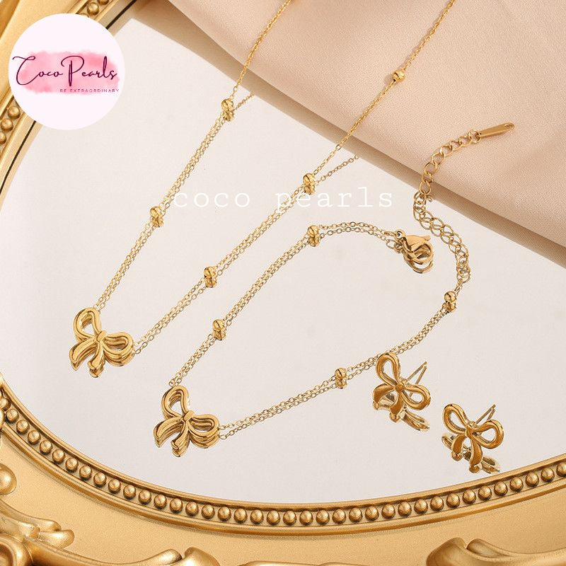 Coco Pearls Stainless Steel Anti tarnish Gold bow necklace set with bow designs on a decorative stand