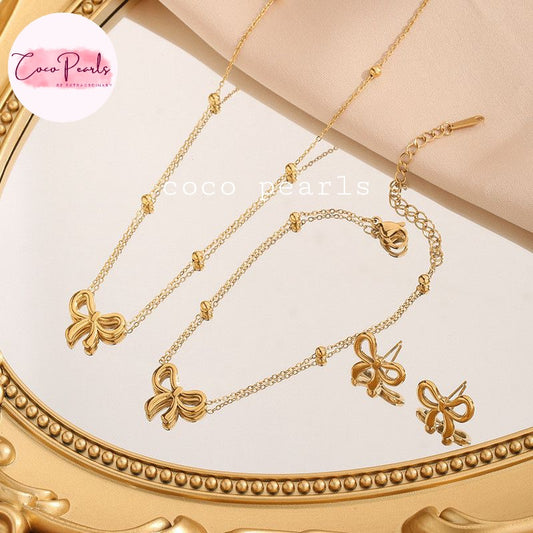 Coco Pearls Stainless Steel Anti tarnish Gold bow necklace set with bow designs on a decorative stand