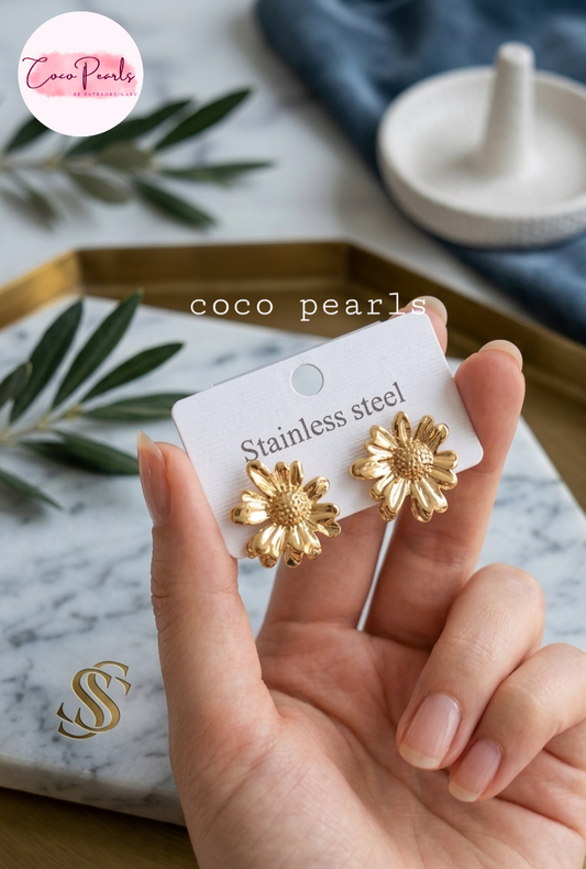 coco pearls stainless steel jewelry pakistan anti tarnish waterproof Golden daisy flower-shaped earrings held by a hand with a simple