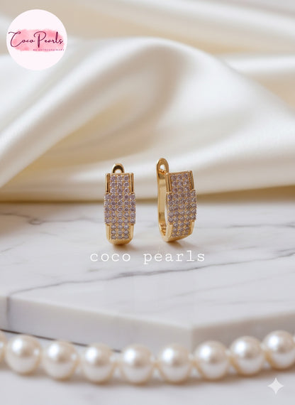 Coco pearls Gold plated hoop earrings with clear stones on a marble surface