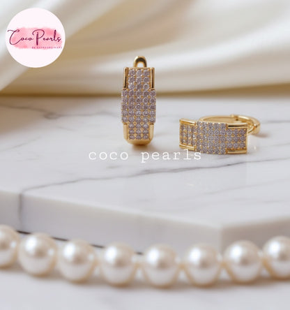Coco pearls Gold plated hoop earrings with clear stones on a marble surface