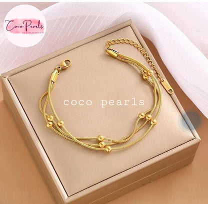 Coco Pearls Stainless steel Anti Tarnish Golden harmony bracelet 3 layer ball chain on a beige box