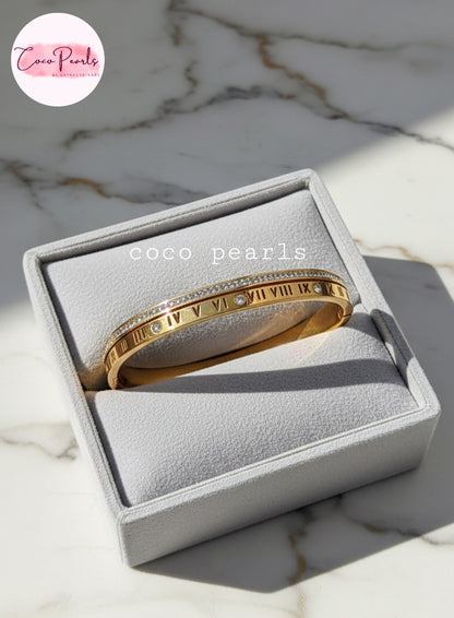 coco pearls stainless steel anti tarnish golden hour handcuff with roman number and diamond studded line displayed in a jewelry box