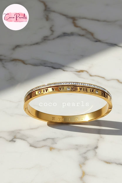 coco pearls stainless steel anti tarnish golden hour handcuff with roman number and diamond studded line displayed on marble surface