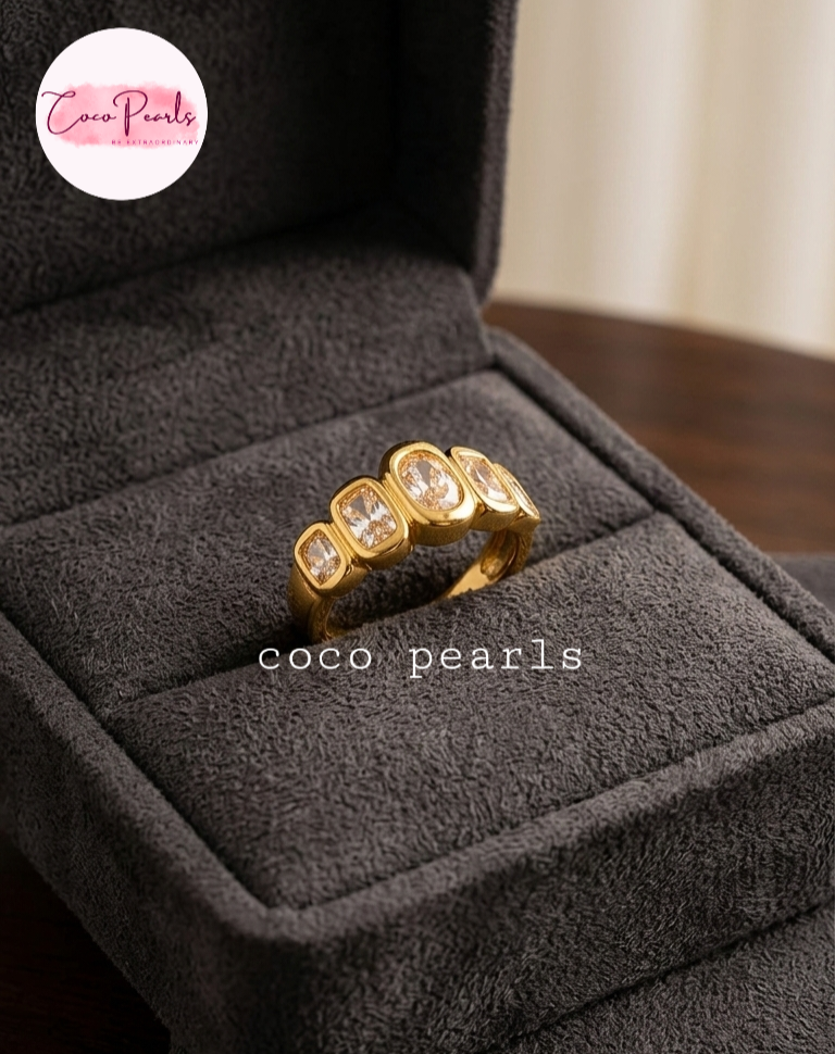 coco pearls stainless steel anti tarnish golden quad ring with diamonds on a grey jewelry box
