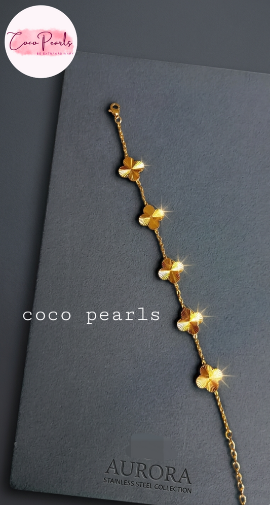 coco pearls stainless steel jewelry pakistan anti tarnish waterproof gold essence clover bracelet displayed on metallic background