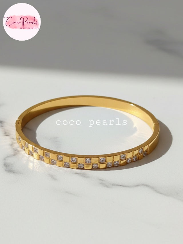 Coco Pearls Stainless Steel Anti tarnish gold grid spark handcuff with diamond grid design on marble surface