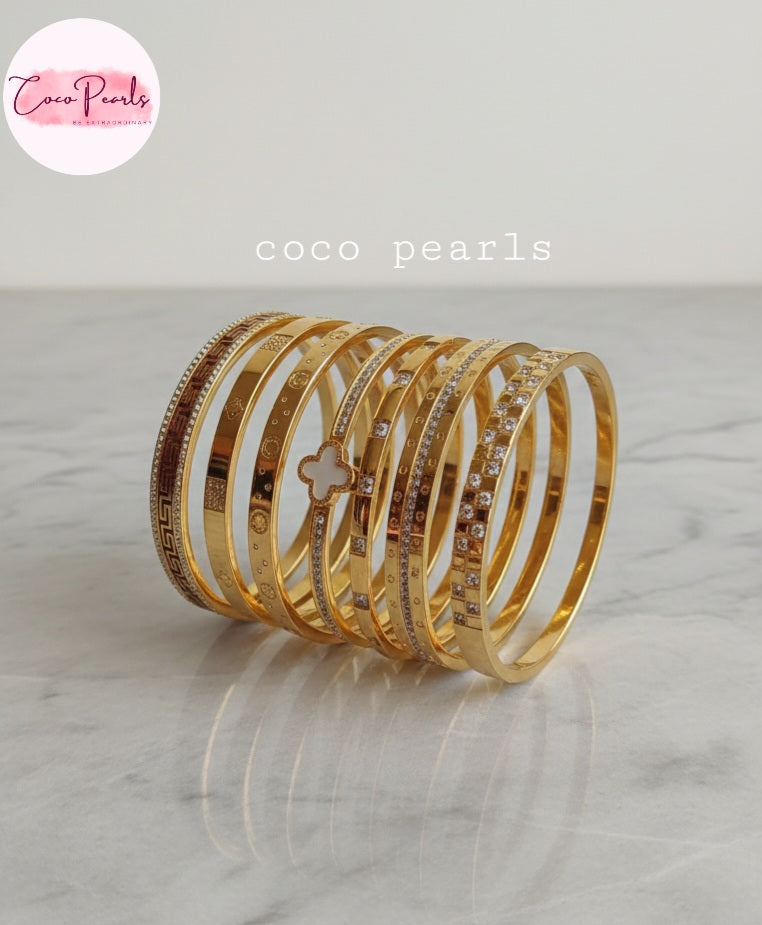 Coco Pearls Stainless Steel Anti tarnish gold stack of handcuffs displayed on marble surface